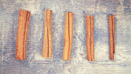 Vintage stylized cinnamon sticks on wooden background