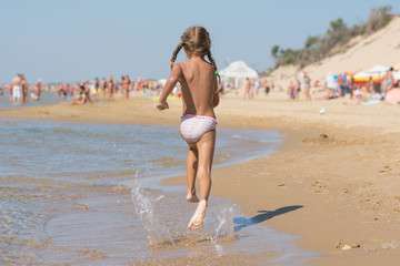 Six year old girl running on the beach