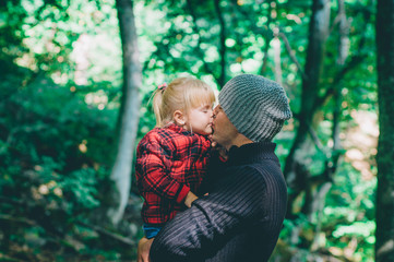 Young father kissing his little daughter having fun in the fores