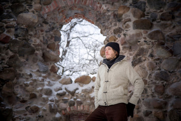 Handsome man at stone wall in the old castle in winter day