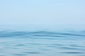 Poster Ruhige Meeresoberfläche. Seelandschaft in den frühen Morgenstunden bei klarem Himmel. © Vitalii
