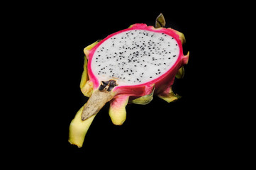 Fresh dragon fruit cut in half on a black background closeup