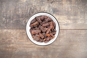 Dried raisins in a bowl on wooden background