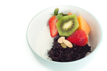 Healthy asian or Thai style breakfast porridge of black rice, also known as Forbidden Rice, with coconut cream and fresh fruit and nuts.