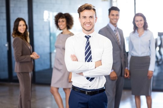 Businessman smiling at camera while his colleagues posing in bac