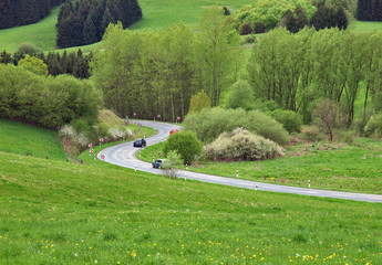 Autos auf kurviger Landstraße in hügeliger Landschaft