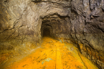Old abandoned iron mine tunnel passage with yellow brimstone