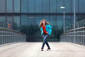 Beautiful blonde woman wearing blue jacket, orange pullover and blue jeans on the street