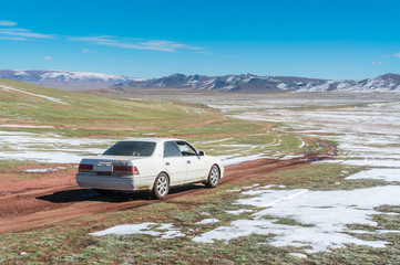 Plakat The car moves on a gravel road in the wilderness against the bac