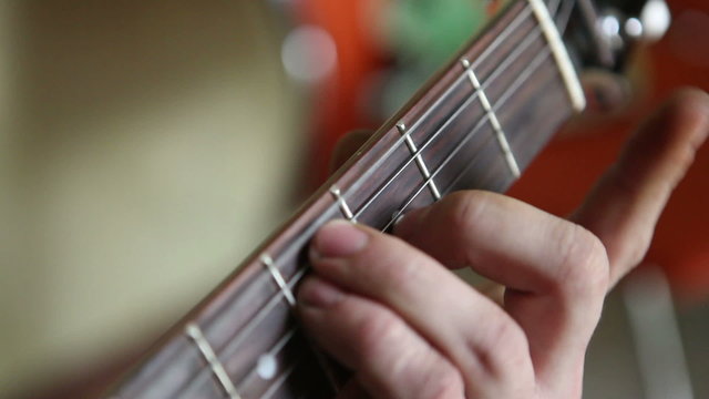 man plays guitar, his fingers on the fretboard closeup