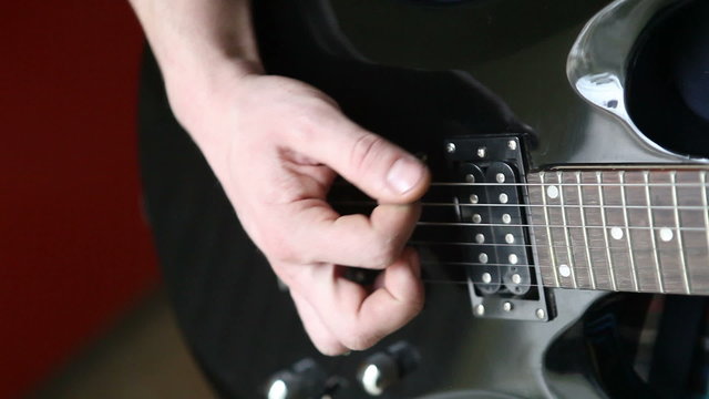 man playing mediator the electric guitar close-up
