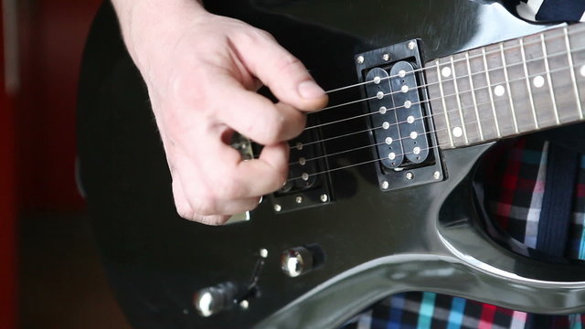 man playing mediator the electric guitar close-up