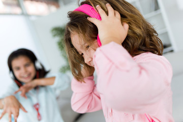 Two young sisters listening to music and dancing at home.