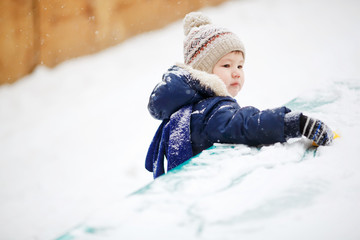 Little boy playing alone with toy in snow, close up. Outside, winter. 