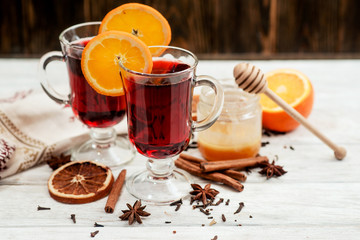 
mulled wine with oranges , honey , cinnamon and cloves on a wooden background   