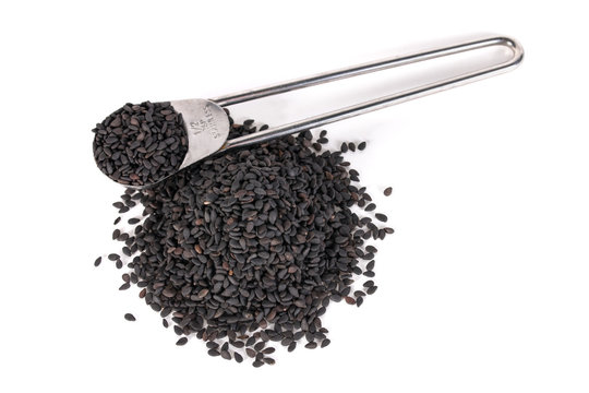 black sesame isolated on white background with copy space. metal measuring spoon of sesame seeds and heap of sesame seeds.