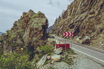 Picturesque mountain landscape with roadside red and white triple chevron sign warning for...