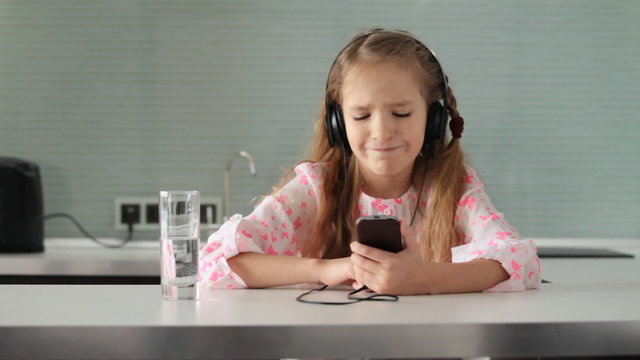 Girl listening to music on the phone. Child with headphones