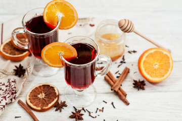
mulled wine with oranges , honey , cinnamon and cloves on a wooden background   