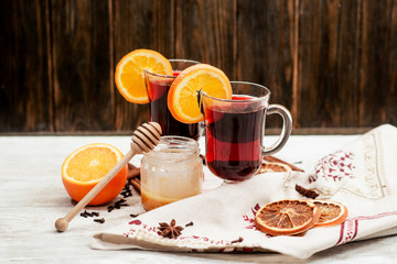 
mulled wine with oranges , honey , cinnamon and cloves on a wooden background   