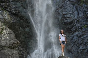 Fototapeta na wymiar girl on rock with waterfall background