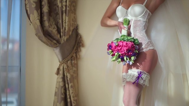 Bride Near Wedding Bouquet of Flowers. The Bride in Lingerie.