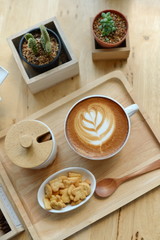hot latte art  with cactus in coffee shop on table wooden
