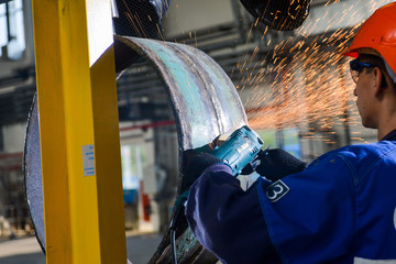 Worker cutting metal with grinder. Sparks while grinding iron
