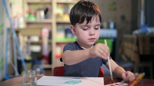  boy at the table draws with a brush