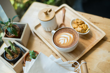 hot latte art  with cactus in coffee shop on table wooden
