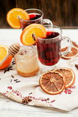 
mulled wine with oranges , honey , cinnamon and cloves on a wooden background   