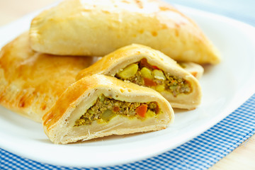 Tasty cake stuffed with meat on a white plate and blue checkered