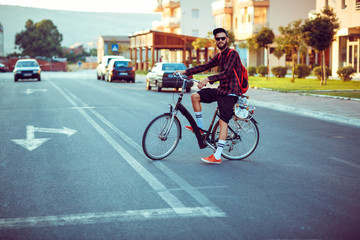 Fototapeta premium Young man in sunglasses riding a bike on city street