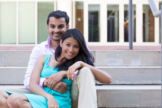 Closeup Portrait, Attractive Wealthy Successful Couple In Pink Shirt And Green Dress Holding Each Other Smiling, Isolated Outside Stairwell Background.