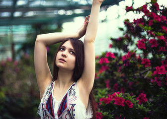 Naklejka premium Young pretty girl posing near beautiful leaves and flowers