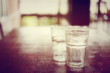 Drinking cold water into a three glass placed on the wooden tabl