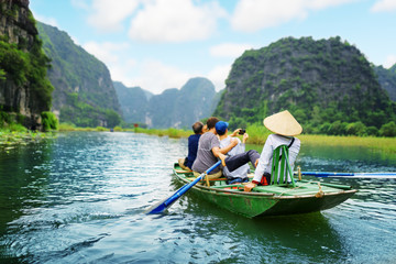 Tourists taking picture. Rower using her feet to propel oars