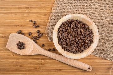 Coffee beans in bowl on wooden background