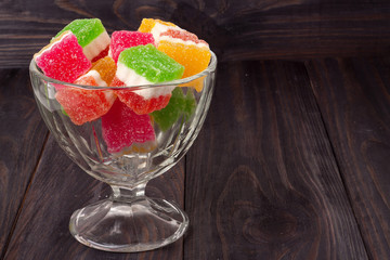 Colorful jelly candy in a glass vase on  wooden background
