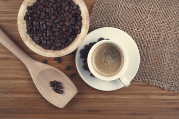 Coffee beans in bowl on wooden background