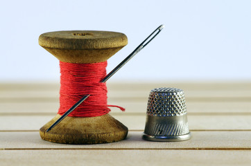 Vintage spool of thread with needle closeup. Tailor's work table, textile or fine cloth making.