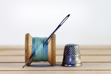 Vintage spool of thread with needle closeup. Tailor's work table, textile or fine cloth making.