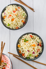 Asian noodles and vegetables on a white wood
