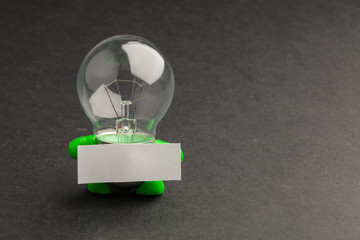 Glass lamp on a black background with green hands and feet holdi