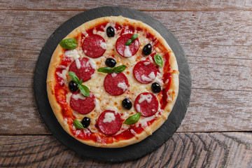 pizza with salami tomato and cheese on a black stone