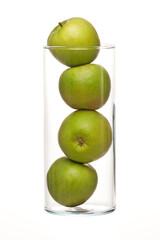 Glass bowl filled with green apples, isolated on white.