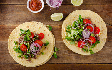 Two mexican tacos on a rustic wooden table.