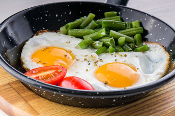 Fried egg on a pan served with tomato and asparagus