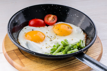 Fried egg on a pan served with tomato and asparagus