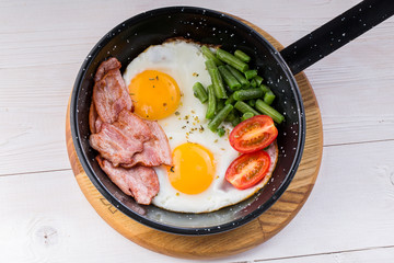 Fried egg on a pan served with tomato and asparagus